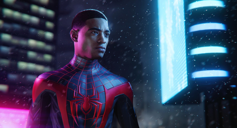 Miles Morales aka Spider Man stands against a glowing skyscraper backdrop with his hood removed so you can see his face