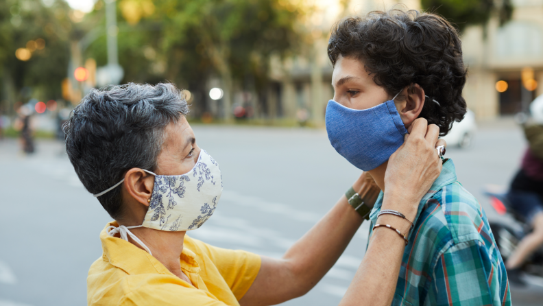 Woman putting face mask on child