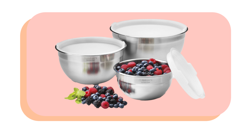 Set of three stainless steel mixing bowls with lids and one bowl has mixed berries inside.