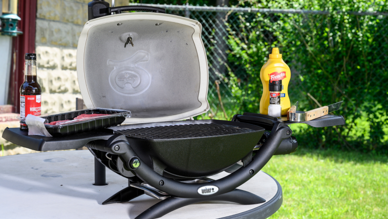 Weber Q 1200 portable gas grill open, on an outdoor table.