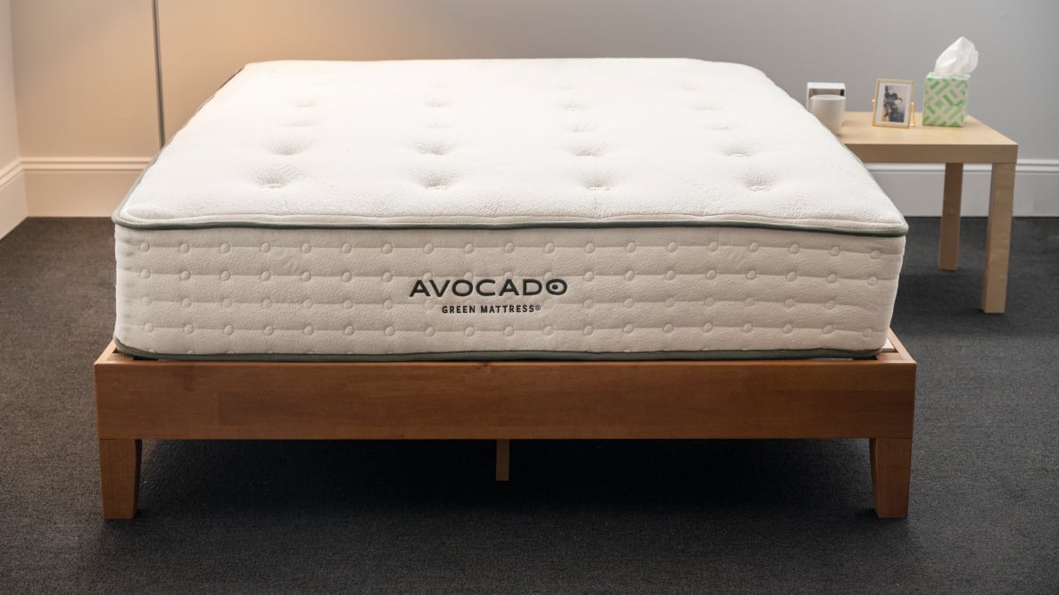 Bare avocado green mattress on a bed frame next to nightstand