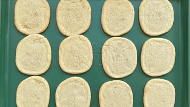Sugar cookies on a green cookie sheet.