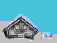 A snowed-in cabin in a winter landscape in front of a blue-checkmark Reviewed background.
