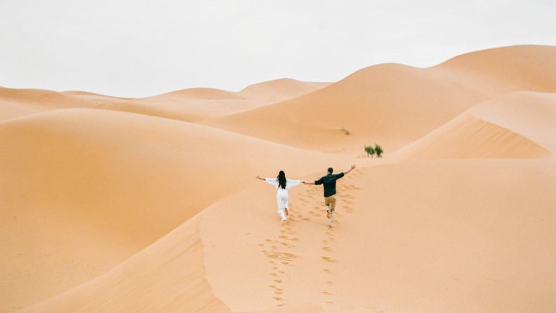 A couple wanders the Sahara Desert together.