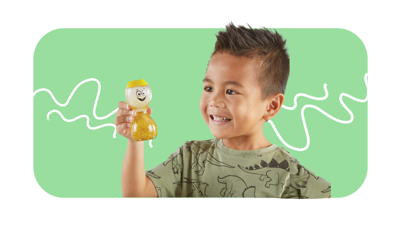 Small child smile while holding up yellow hourglass-shaped bottles filled with liquid.