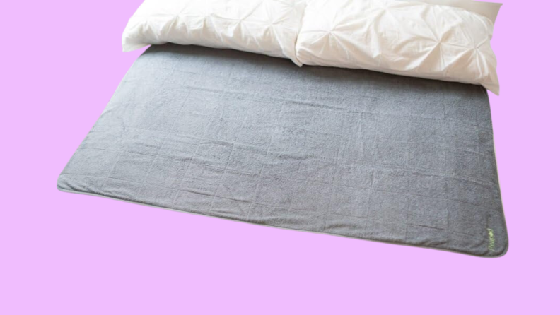 A gray extra-large mattress pad on a purple background.