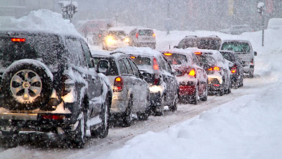 A line of cars in traffic during a snowstorm.