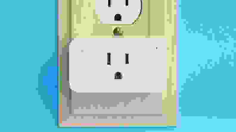 White, rectangular wall plug plugged into outlet on blue wall.