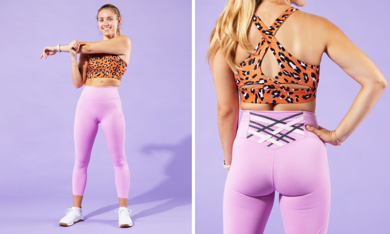 A woman stretching her arm in purple Fabletics leggings and an orange Fabletics sports bra.