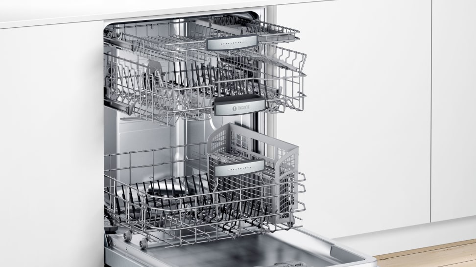 A dishwasher with three racks stands open in a kitchen