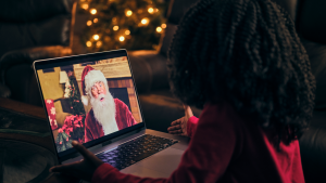 一个小孩看着笔记本电脑上的圣诞老人的图像。