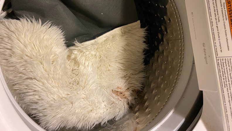 Stained white shag rug in drum of  washer machine.