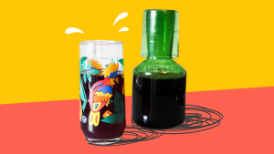 一个装满冰镇木槿花茶的彩色玻璃杯，旁边是一个绿色的玻璃瓶，里面装满了更多同样的东西。