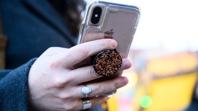 A person uses a mobile phone with a Popsocket.