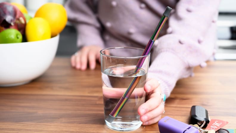 A person holds a glass with a reusable straw.