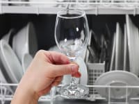 Someone examines a wine glass upon taking it out of a high end dishwasher.