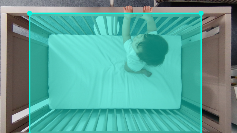 an aqua rectangle overlays a baby in a crib