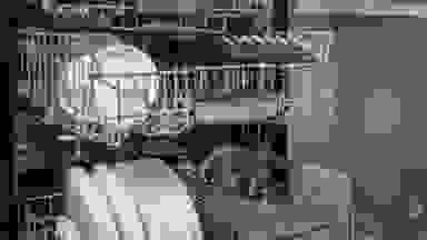 A dishwasher with three racks stands open in a kitchen