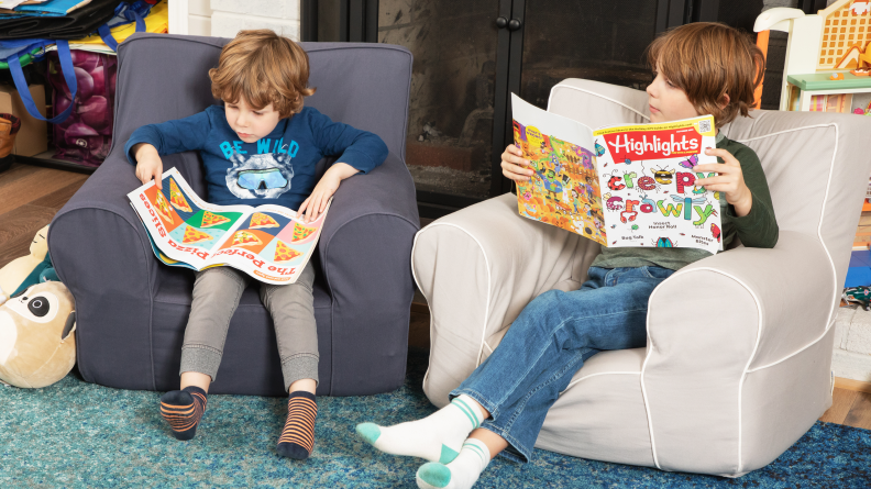 Two children sit in small chairs reading Highlights magazines.
