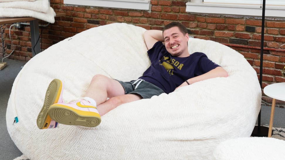A man smiling while he's laying on the bean bag.