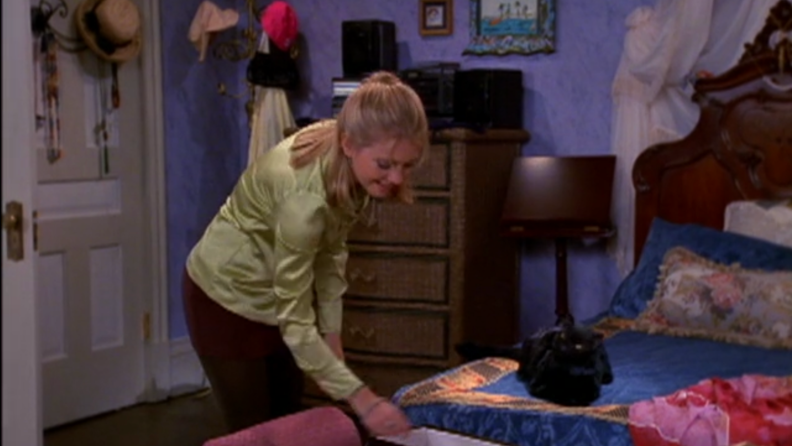 A still from Sabrina featuring Sabrina talking to Salem in her bedroom.