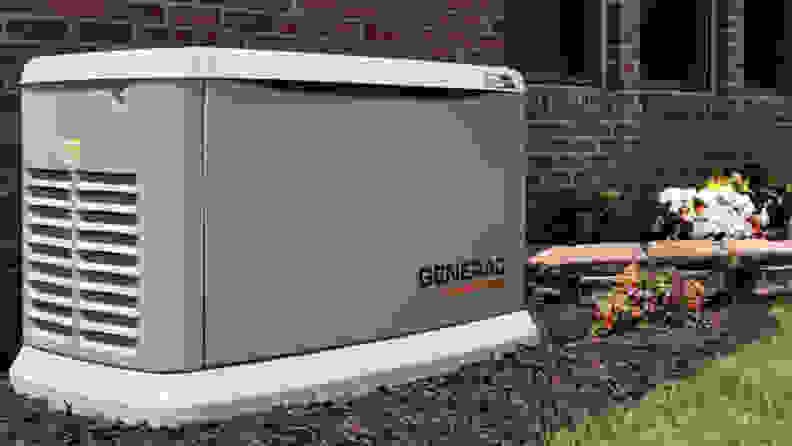 A standby generator made by Generac, sitting against the outside wall of a home.