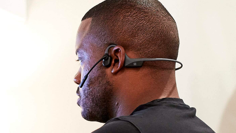 A person wears a pair of headphones with back turned to the camera.