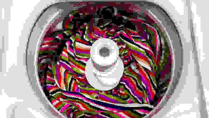 A top-down shot of the interior of the Maytag MVWP576KW Top-loading Washing Machine with Pole Agitator, with a colorful blanket placed in the drum.