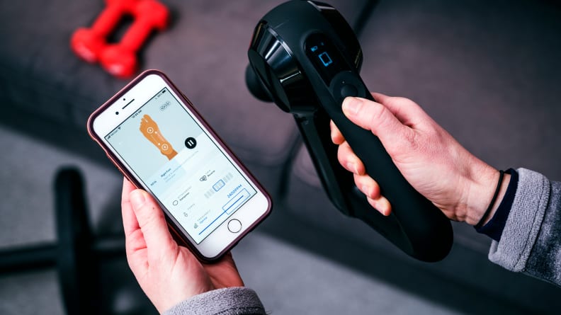 A woman connecting the Theragun Elite massage gun to the Therabody app.
