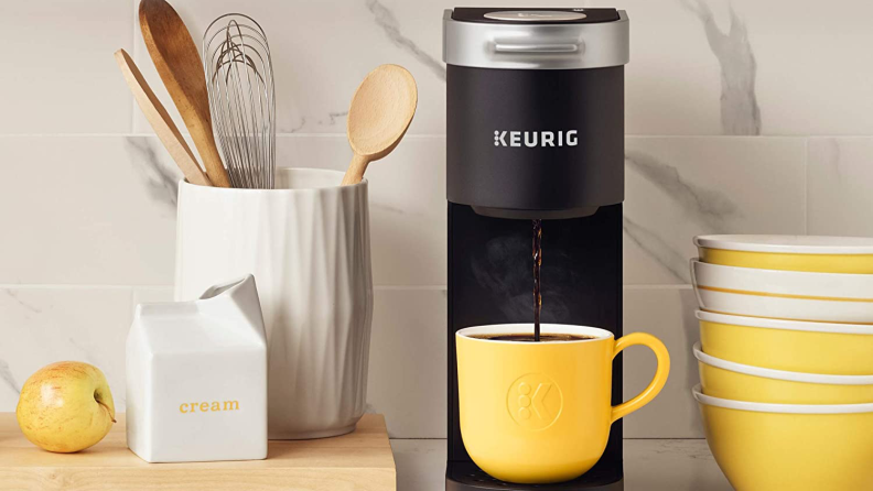 A yellow coffee cup sitting on a Keurig coffee maker in a cozy kitchen.