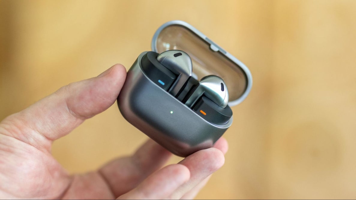 A hand holding up an open case with the earbuds inside.