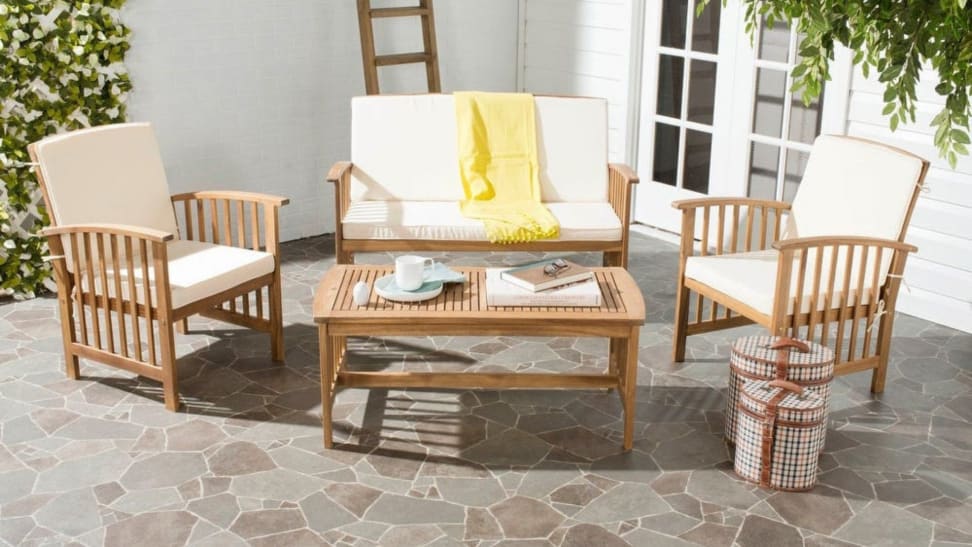 A set of Safavieh wooden patio furniture with white cushions is arranged on an outside patio.