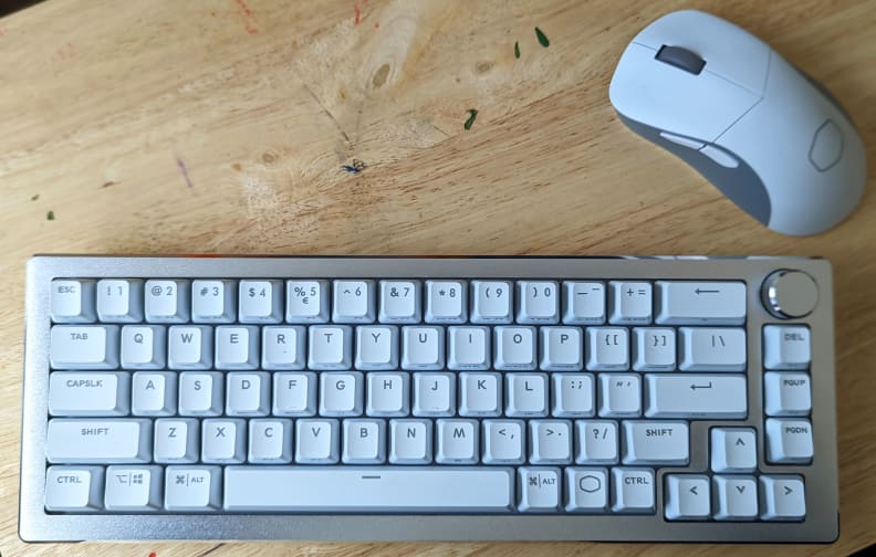 A white keyboard with a white mouse on top of a light brown desk