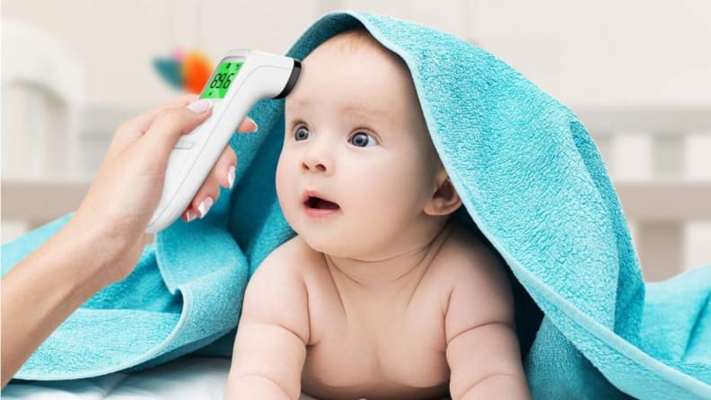 Baby peeking out from under a blue blanket getting their temperature read