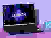 Black Lenovo Legion Pro 5i Gen 8 gaming laptop opened with desktop screensaver on screen next to blue acrylic paperweight in the middle of purple setting.