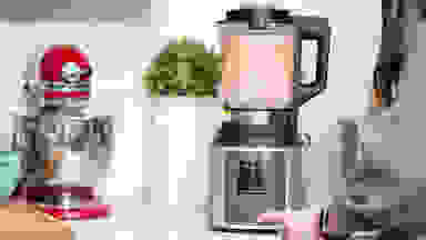 A person blends a smoothie in a blender on a countertop surrounded by other kitchen items.