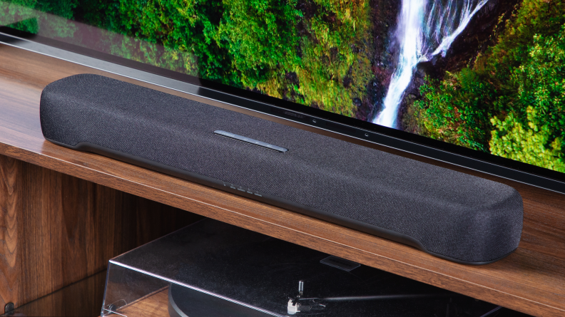 The Yamaha SR-C30A on a wooden table in front of a TV shot from an angle to the right.