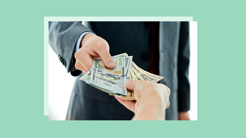 A stock photo of money being exchanged between two hands, set against a green background.