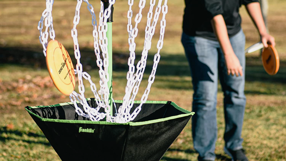 Photo of a young model in a black polo enjoying the Franklin Sports Disc Golf Basket.
