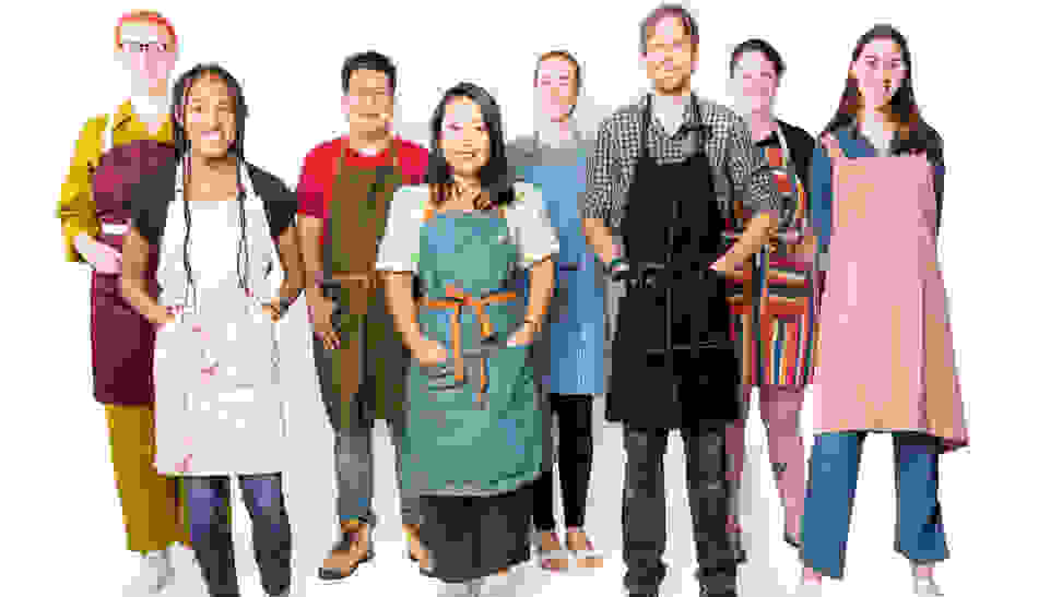 A group of people poses wearing aprons.