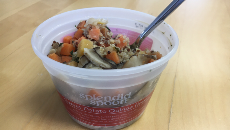 Splendid Spoon sweet potato quinoa bowl in a plastic container on a wooden surface.