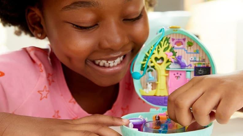 Young child playing with small Polly Pocket toy.