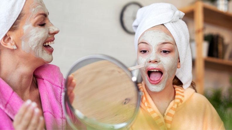 Mother and daughter with face masks and towels on their head having a spa day