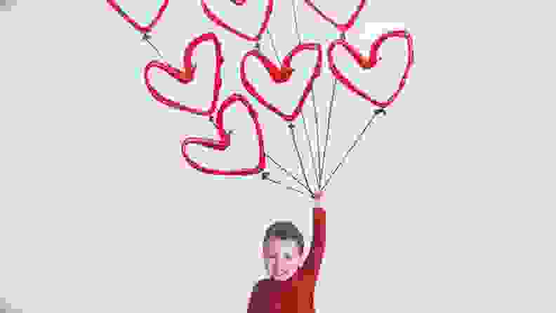 A card of a child holding heart balloons.
