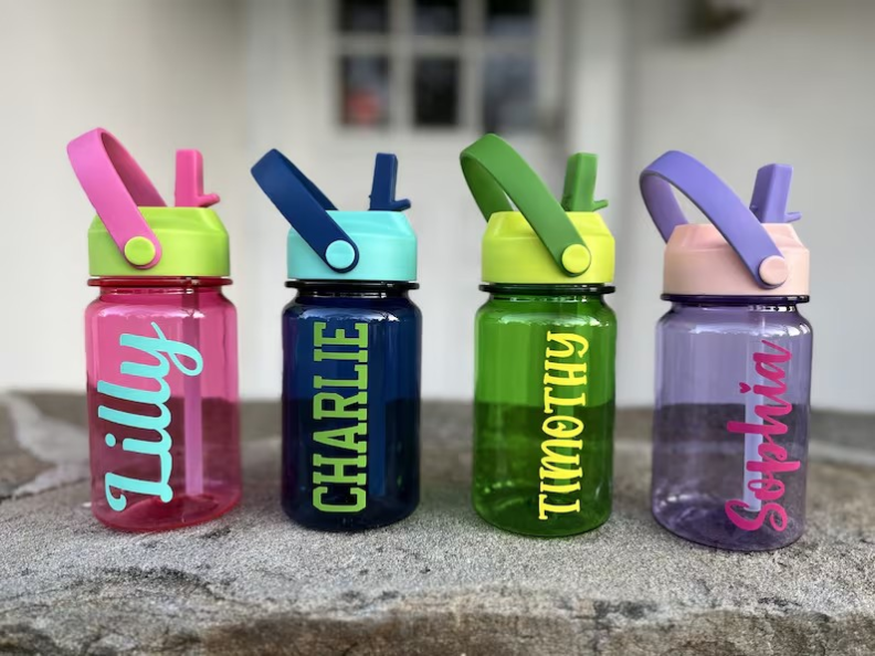 Four water bottles with names printed on them in white paint.