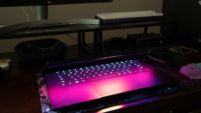 A picture in a dark room of the Blade partially closed, its bright screen reflecting off the keyboard and touchpad.