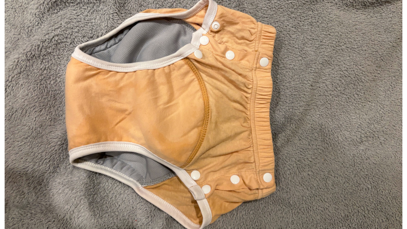 Orange diaper, closed, against a gray fabric surface.