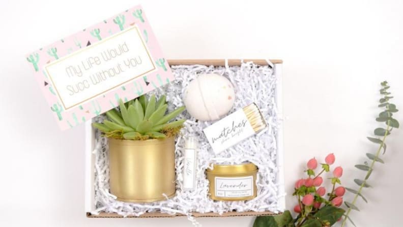 An open gift box shot from above, revealing a succulent, candle, and bath bomb.