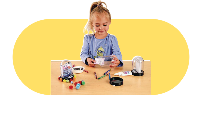 A little girl sitting at a table making a snow globe.