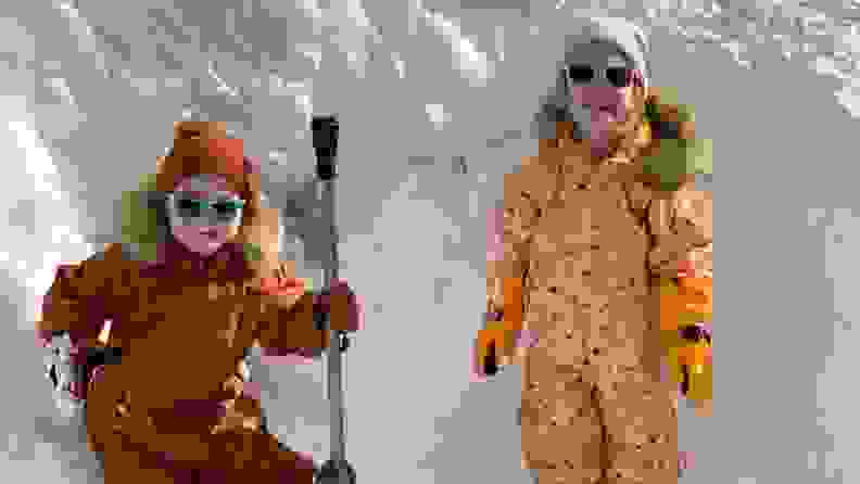 Two children wearing the snowsuit posing in front of snow.